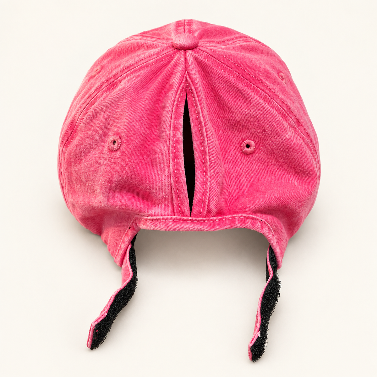 Back view of the hot pink ponytail hat with the vertical hair opening and hook-and-loop strap open.