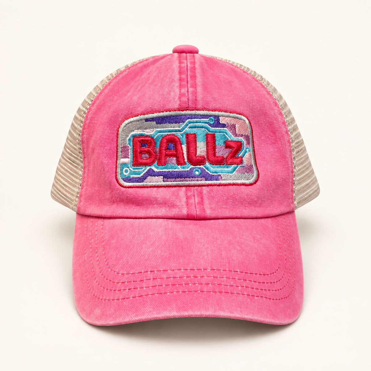 Front view of a washed hot pink baseball cap with colorful BALLz embroidery and light tan mesh panels.