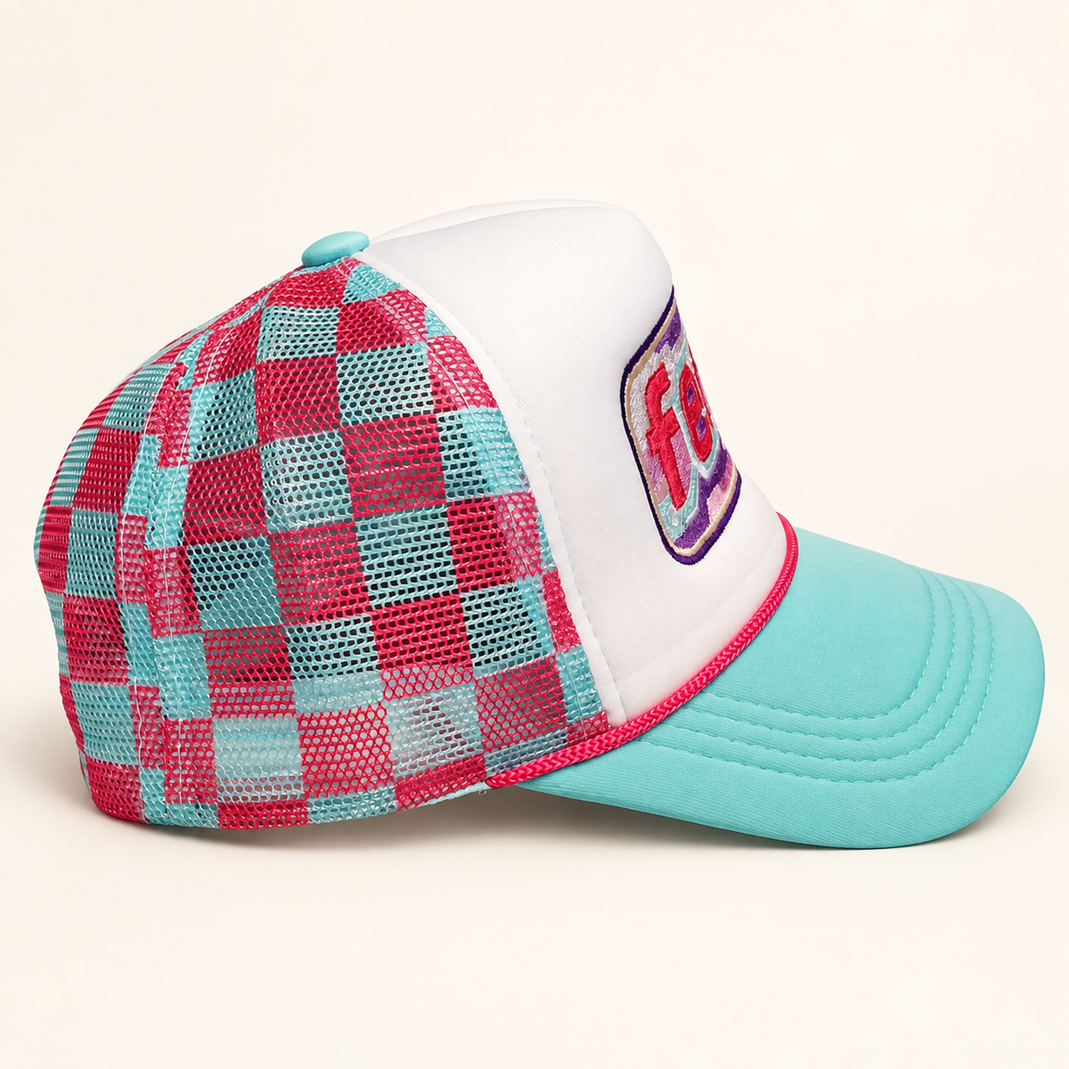 Side view of the aqua FERAL trucker hat highlighting the teal-and-hot-pink gingham mesh panels.