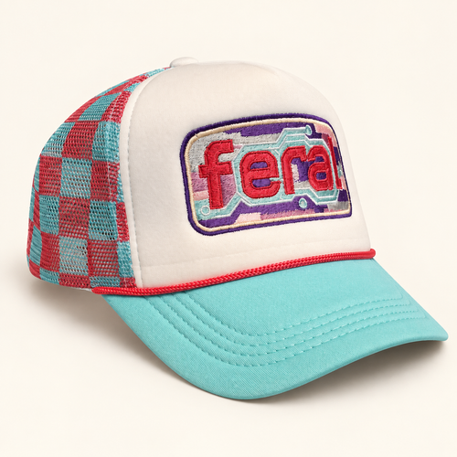 Angled view of a white FERAL cassette embroidered trucker hat with an aqua brim, coral rope, and plaid mesh.