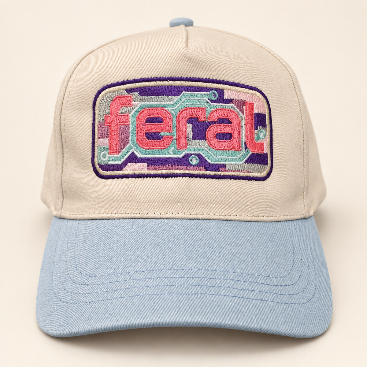 Front view of a cream FERAL cassette embroidered trucker hat with a powder-blue brim.