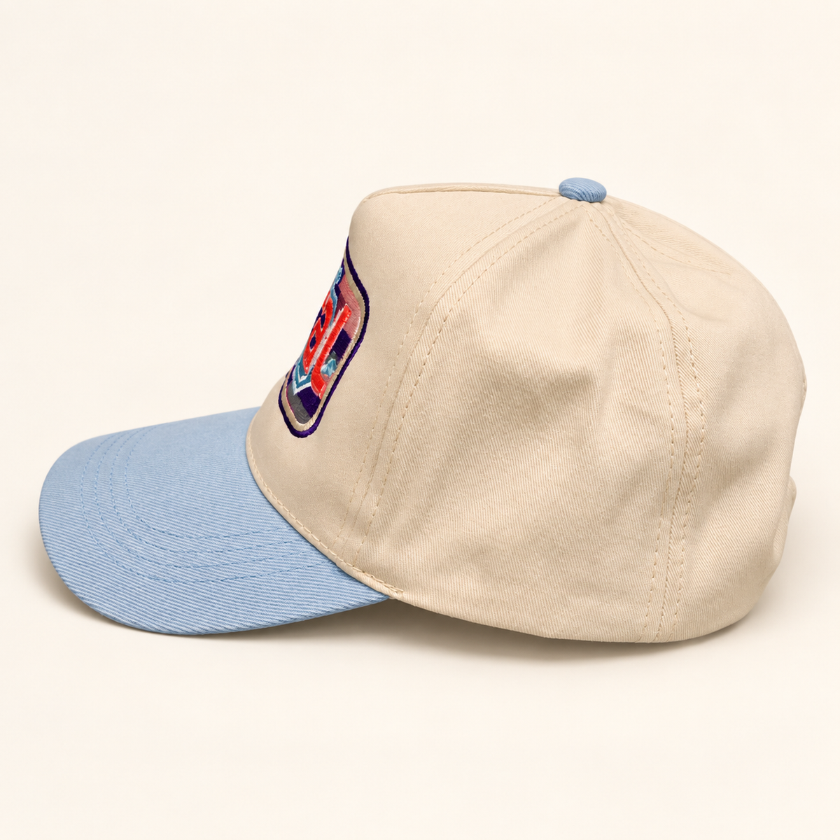 Side and rear view of the powder-blue FERAL hat showing its solid cream fabric panels and blue top button.