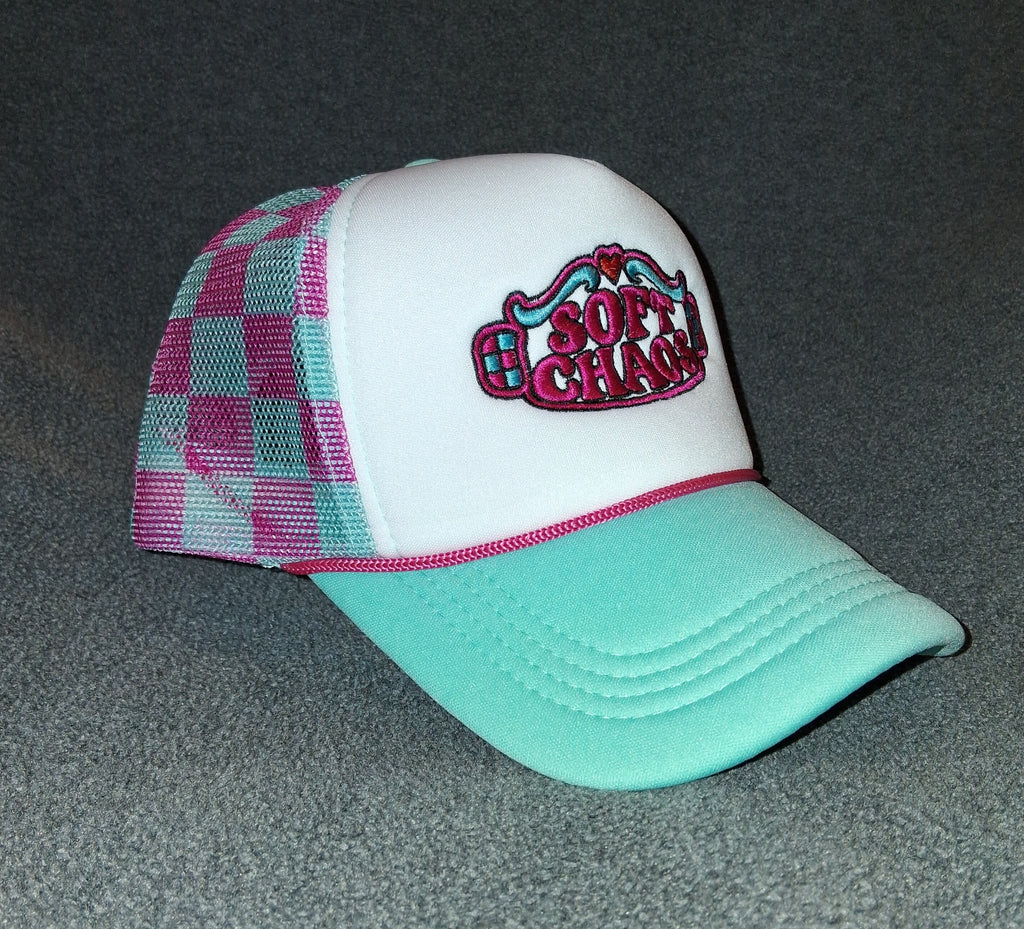 Angled view of the Soft Chaos trucker hat showing hot pink and teal gingham mesh, a teal curved brim and original embroidery.