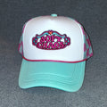Front of the Soft Chaos embroidered trucker hat with hot pink lettering, teal accents, a white front, teal brim and pink-and-teal gingham mesh.